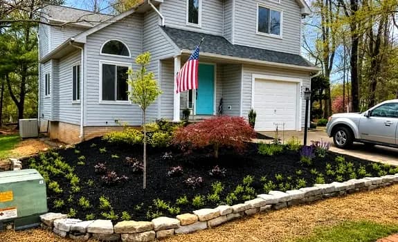 Front-yard landscape design with stacked-stone edging, a red maple, and layered plantings